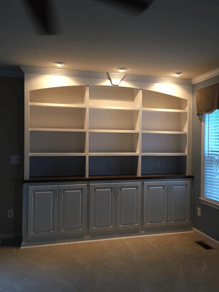 White built-in bookcase with arched header and cabinets below