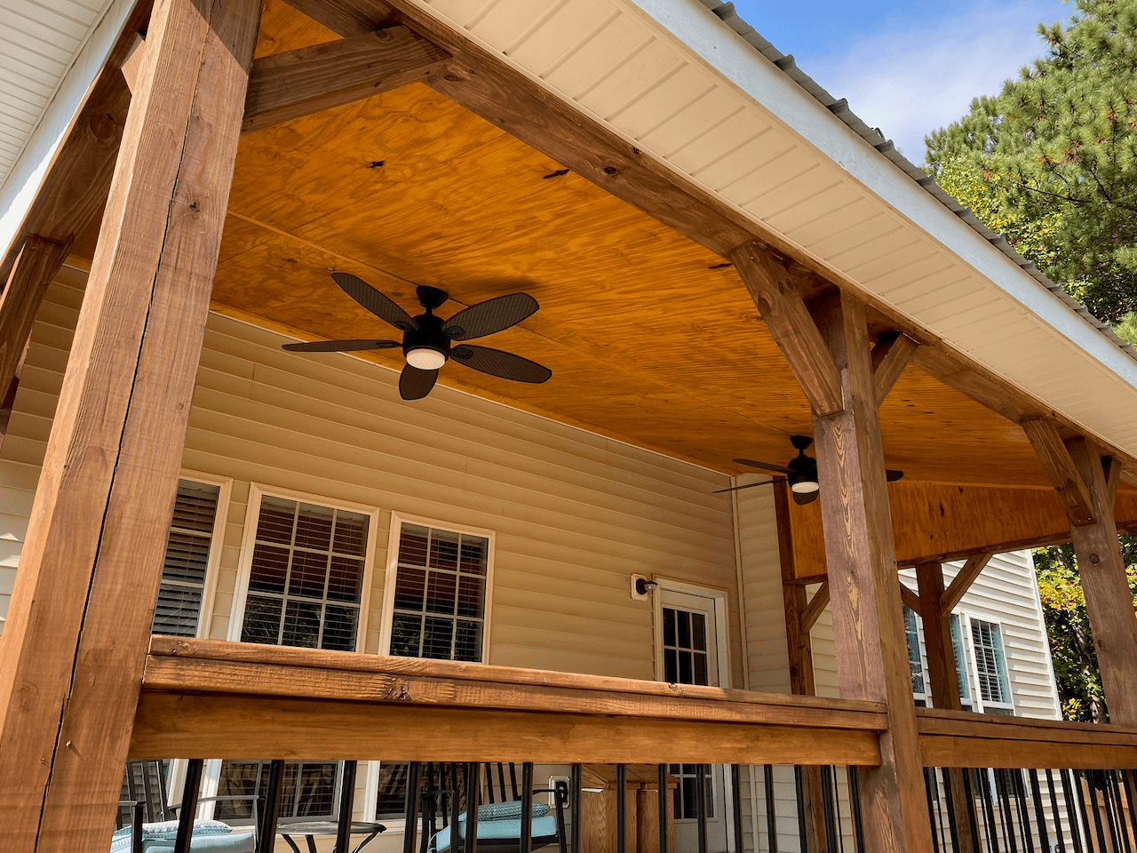 Stained cedar posts and beams under a new covered porch ceiling