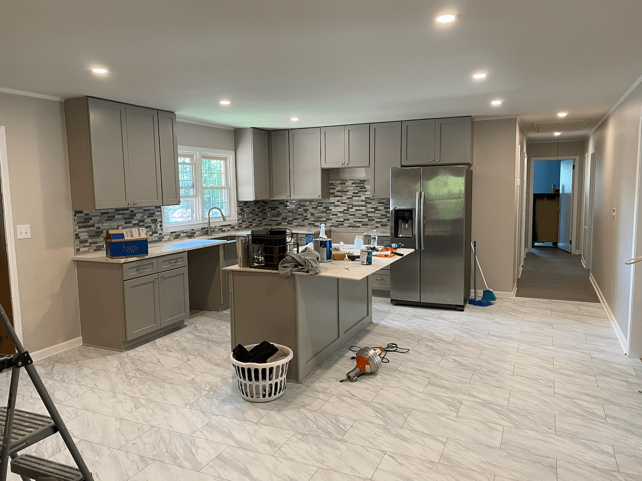 Kitchen remodel with gray cabinets, island and marble-look tile floor