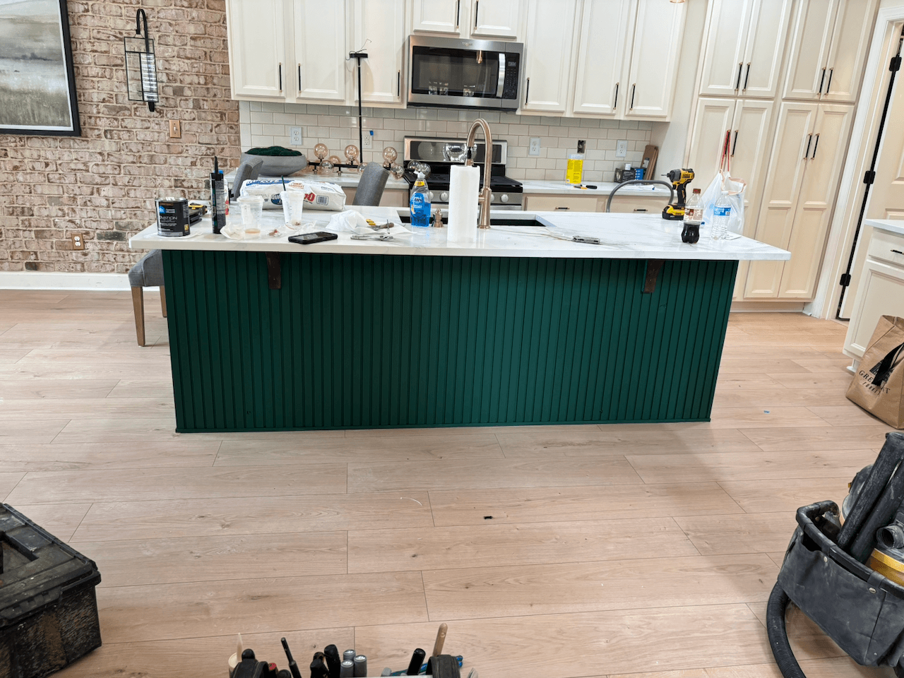 Renovated kitchen with a green beadboard island, white cabinetry and white oak floors